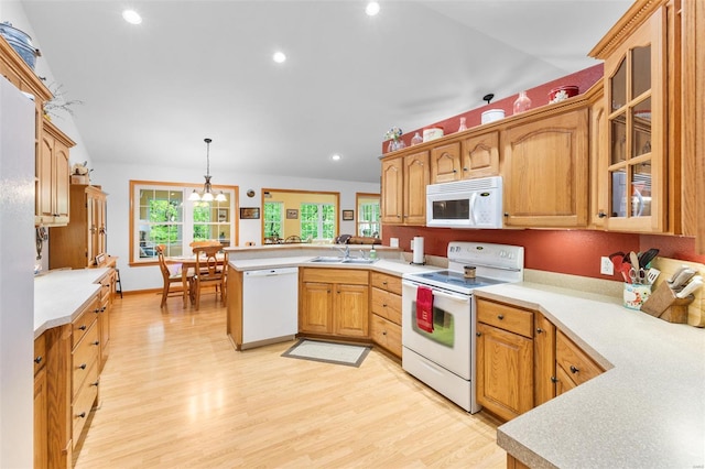 kitchen featuring a peninsula, plenty of natural light, a sink, and white appliances