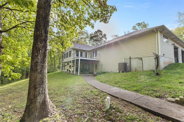 rear view of house featuring cooling unit, a yard, and a balcony