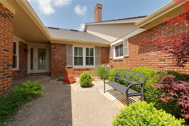 entrance to property featuring a chimney and brick siding
