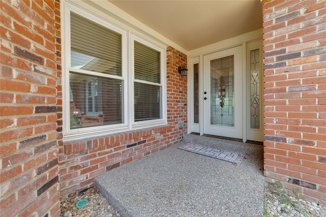 entrance to property featuring a porch and brick siding