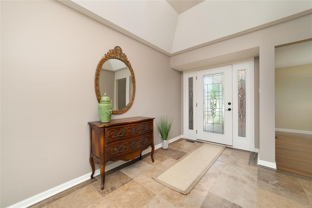 foyer featuring baseboards, a high ceiling, and stone tile flooring