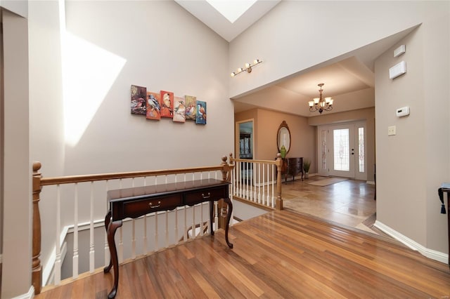 foyer with an inviting chandelier, baseboards, wood finished floors, and a skylight