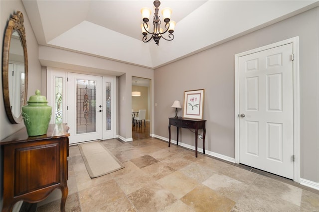 foyer entrance featuring baseboards, a notable chandelier, and stone finish floor