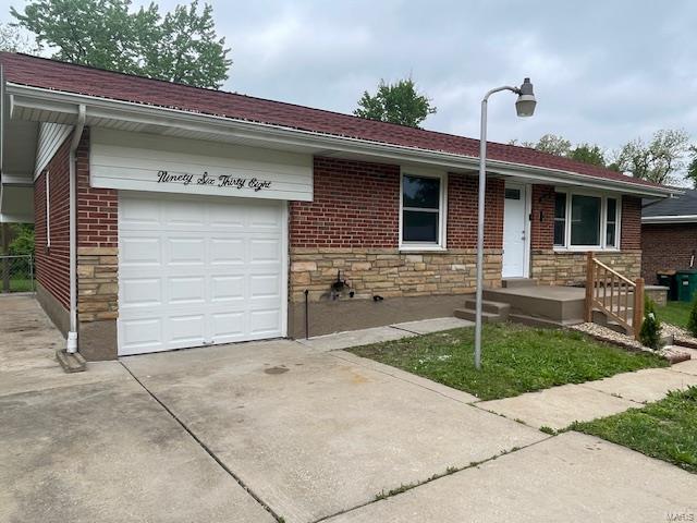 ranch-style house with a garage, concrete driveway, and stone siding