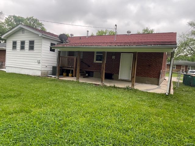 rear view of property featuring a lawn, brick siding, fence, and a patio area