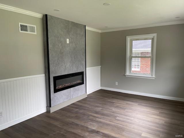unfurnished living room featuring dark wood-style flooring, visible vents, crown molding, a large fireplace, and radiator heating unit