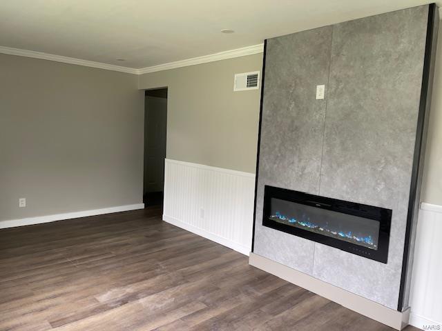 unfurnished living room featuring crown molding, visible vents, wood finished floors, and a tile fireplace