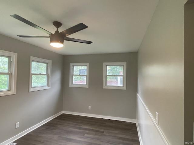empty room with dark wood-style flooring, baseboards, and ceiling fan