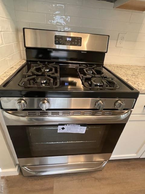 interior details featuring stainless steel range with gas cooktop, backsplash, and light countertops