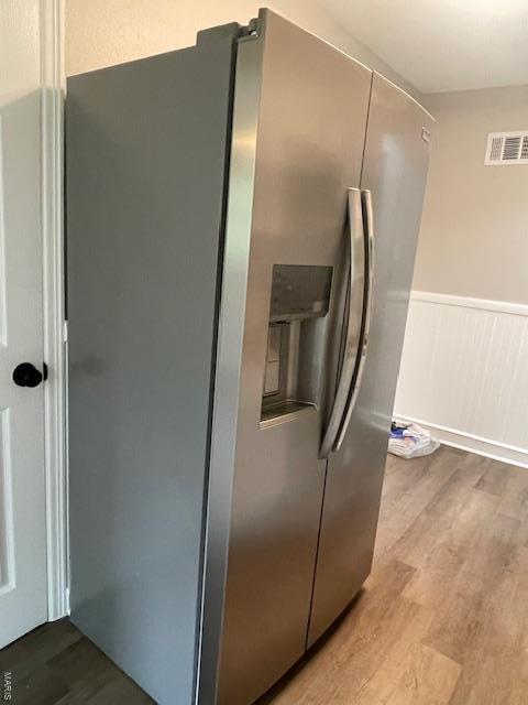 kitchen featuring wainscoting, stainless steel refrigerator with ice dispenser, wood finished floors, and visible vents