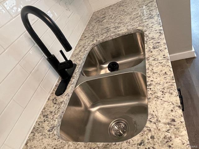 room details with a sink, baseboards, and light stone countertops