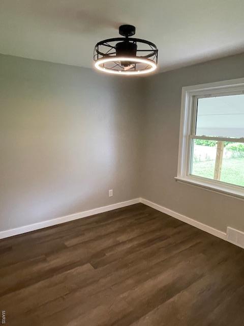 empty room with baseboards and dark wood finished floors