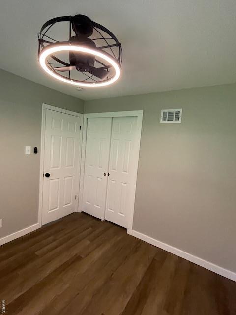 unfurnished dining area featuring baseboards, visible vents, and dark wood finished floors