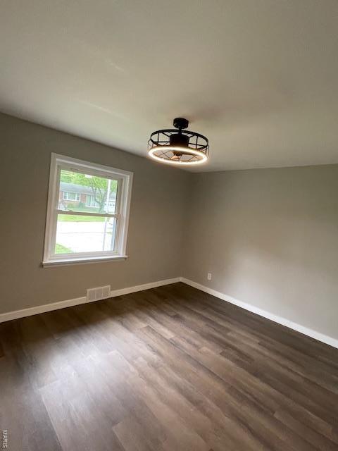 spare room featuring baseboards, dark wood finished floors, ceiling fan, and visible vents