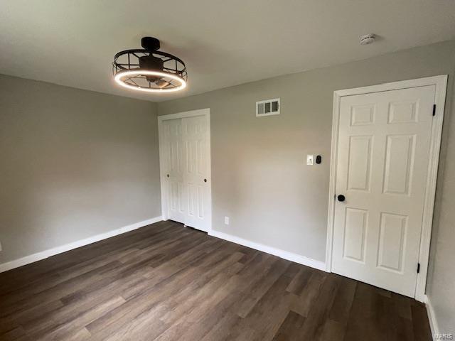 unfurnished dining area featuring dark wood-style flooring, baseboards, and visible vents