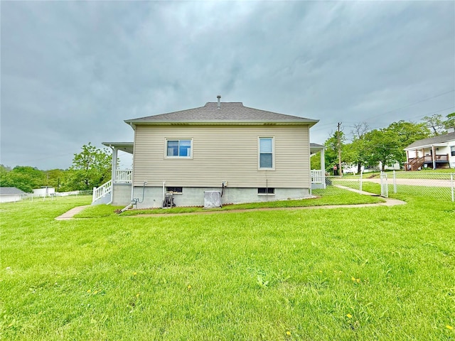back of property featuring a lawn and fence