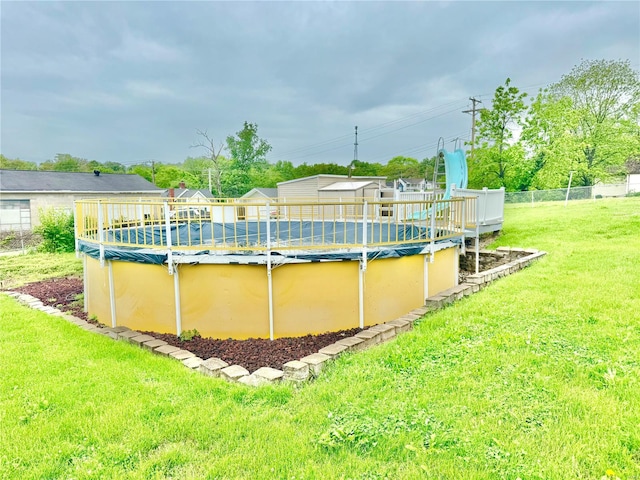 view of swimming pool featuring a yard, fence, and a covered pool