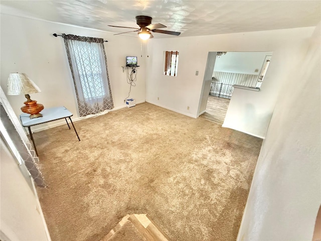 interior space with carpet floors, ceiling fan, and baseboards
