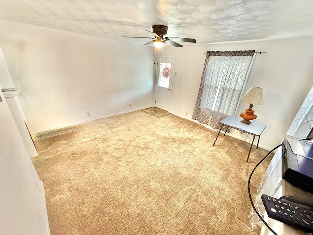 empty room featuring baseboards, ceiling fan, and carpet