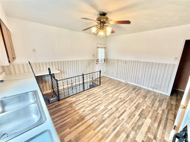interior space with a sink, ceiling fan, and wood finished floors