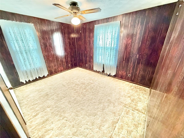 spare room with a ceiling fan and wood walls