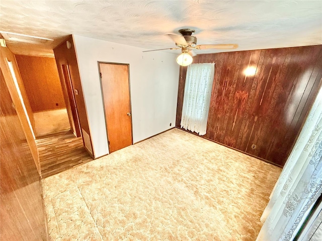 unfurnished bedroom featuring wooden walls and a ceiling fan