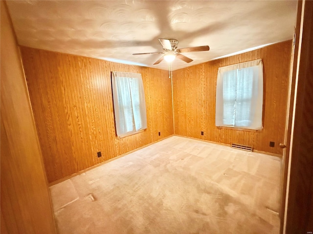 spare room featuring wooden walls, visible vents, a ceiling fan, and a wealth of natural light