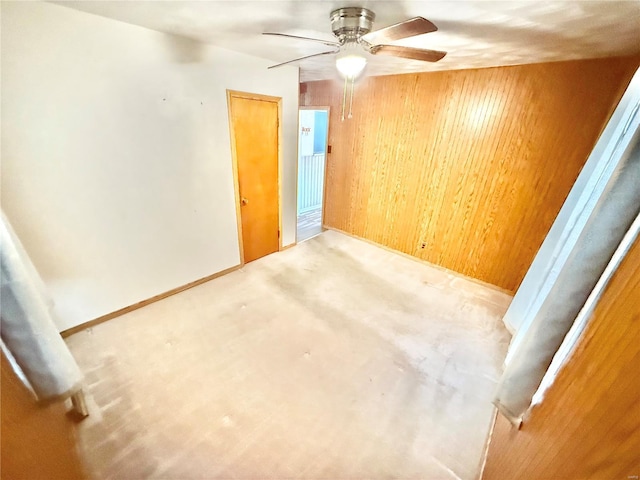 interior space with wooden walls, ceiling fan, and a closet