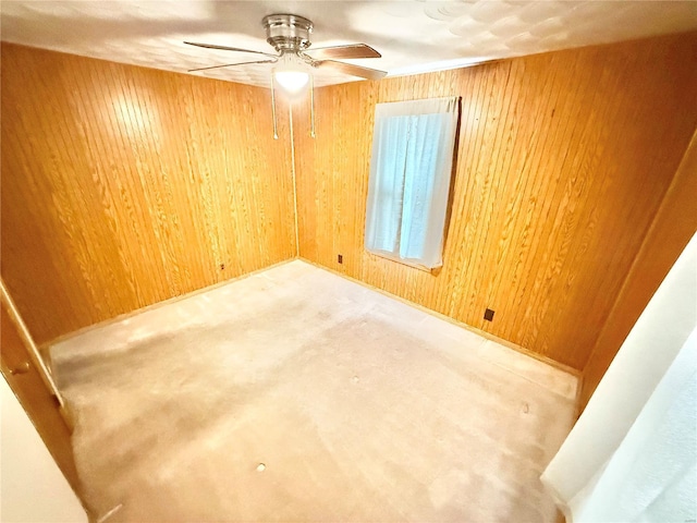 spare room featuring a ceiling fan, carpet, and wooden walls