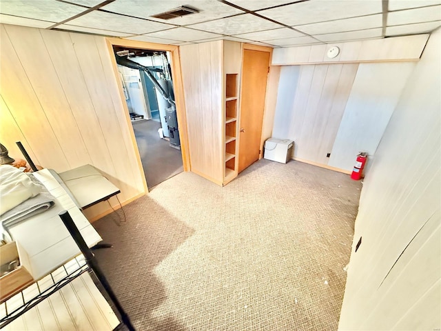 finished below grade area with visible vents, wood walls, and carpet