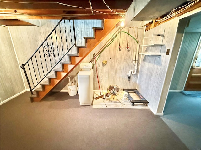 basement with baseboards, wood walls, and stairs