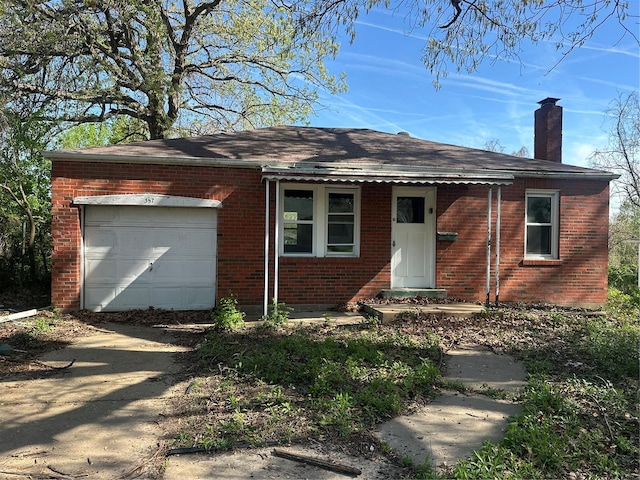 view of front of house with a garage, roof with shingles, a chimney, brick siding, and dirt driveway