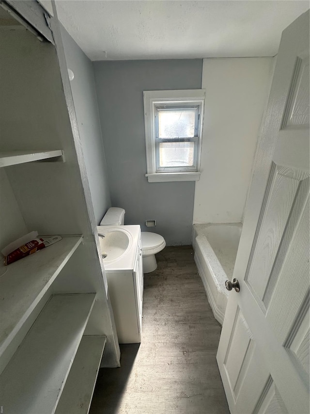 full bathroom with vanity, a bathing tub, toilet, and wood finished floors