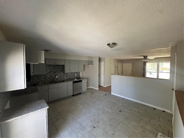 kitchen featuring a ceiling fan, a textured ceiling, tasteful backsplash, a sink, and baseboards