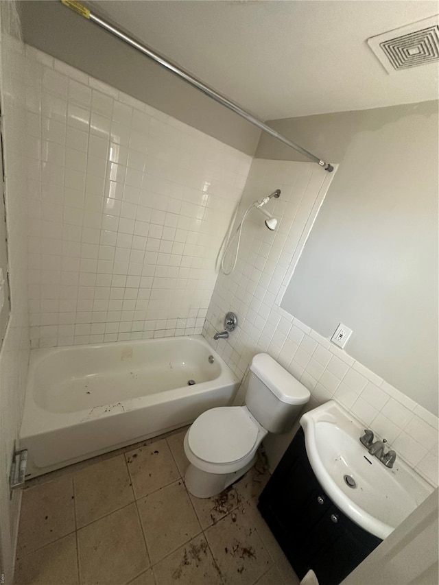 full bathroom featuring visible vents, toilet, tile walls, bathtub / shower combination, and a sink