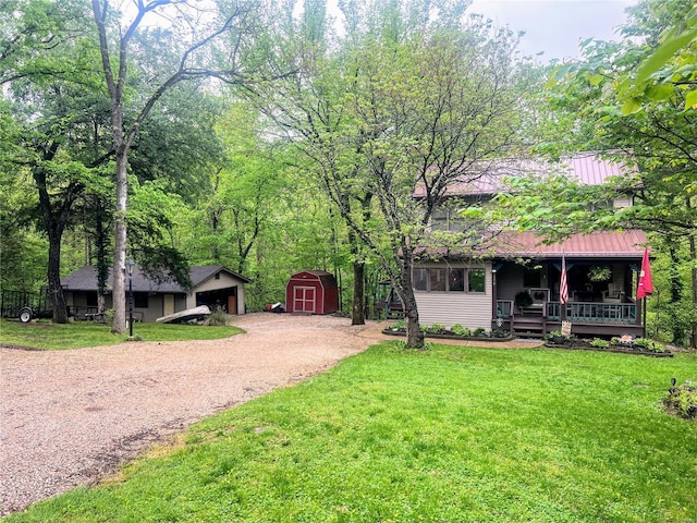 view of front of home with dirt driveway, an outdoor structure, a shed, covered porch, and a front yard
