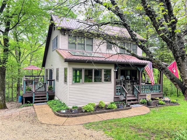 view of front of property featuring a wooden deck, metal roof, and a front yard