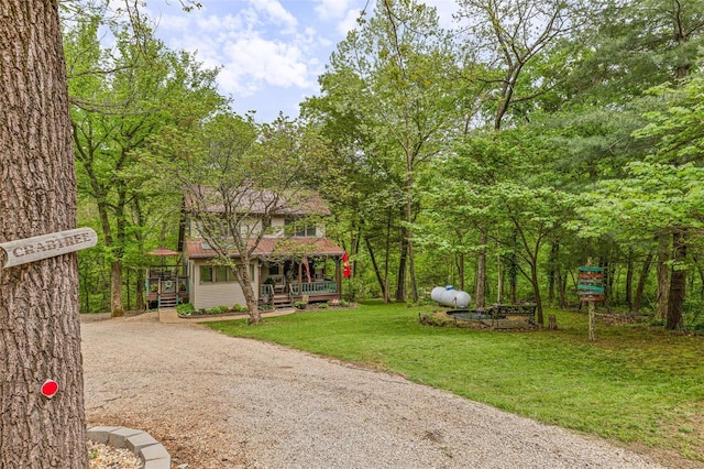 exterior space with covered porch, dirt driveway, and a front lawn