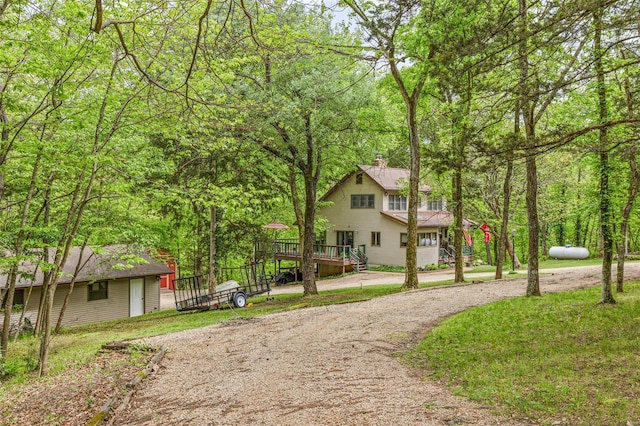 view of property's community with a forest view, a wooden deck, and curved driveway