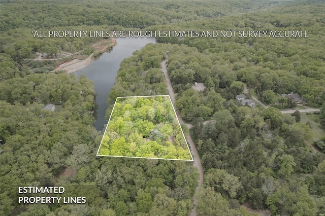 drone / aerial view featuring a wooded view and a water view