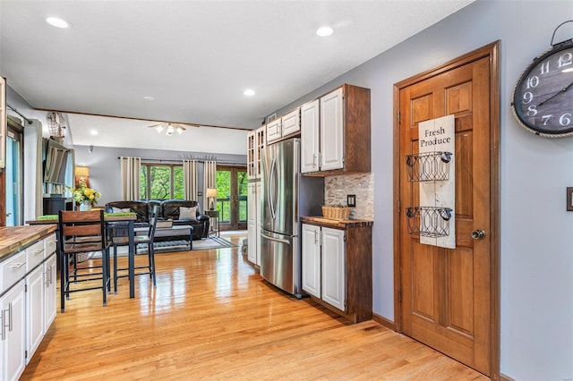 kitchen with freestanding refrigerator, white cabinetry, open floor plan, and light wood-style floors