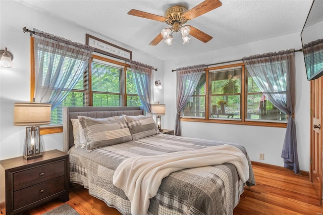 bedroom featuring baseboards, a textured ceiling, a ceiling fan, and wood finished floors