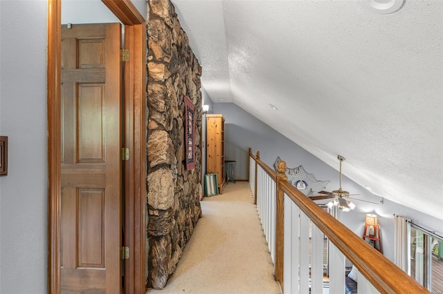 hall featuring light carpet, an upstairs landing, a textured ceiling, and vaulted ceiling