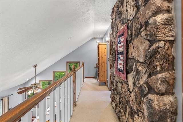 hall featuring light carpet, lofted ceiling, and a textured ceiling