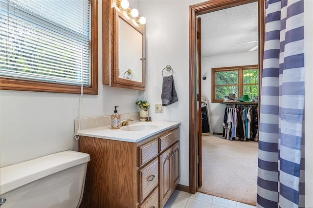 full bath featuring toilet, vanity, and a textured ceiling