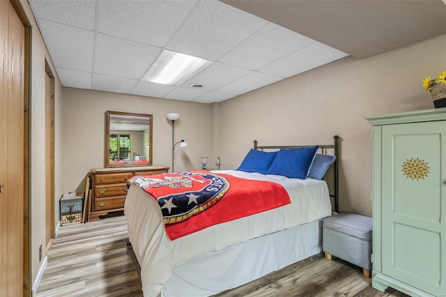 bedroom featuring a drop ceiling and wood finished floors