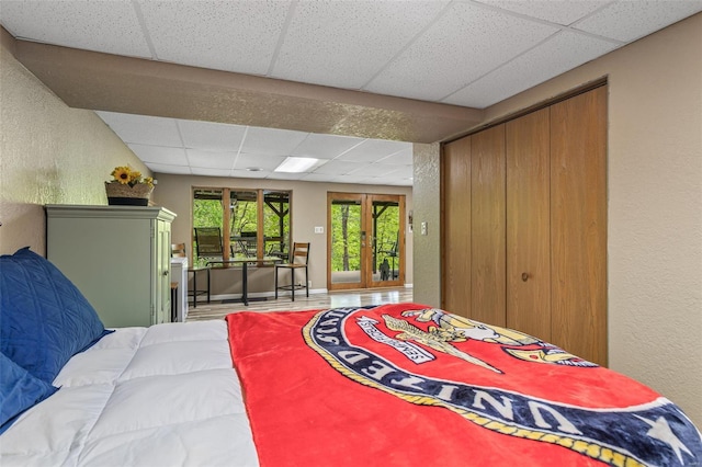 bedroom with a drop ceiling, a closet, and a textured wall