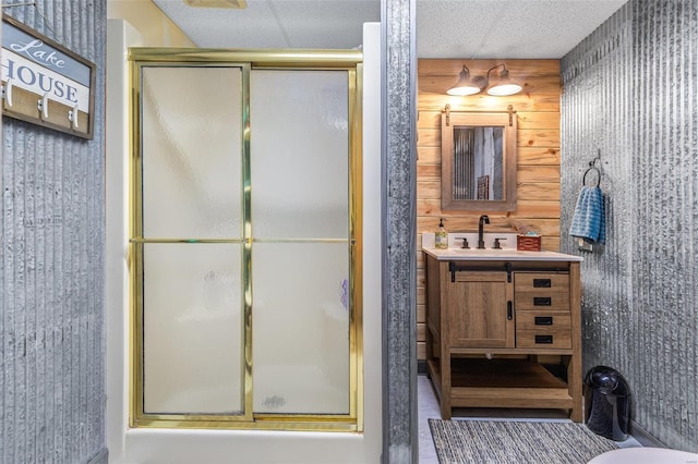 full bath featuring a shower with door, vanity, and wallpapered walls