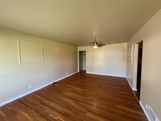 unfurnished room with baseboards, a ceiling fan, dark wood-style floors, and visible vents
