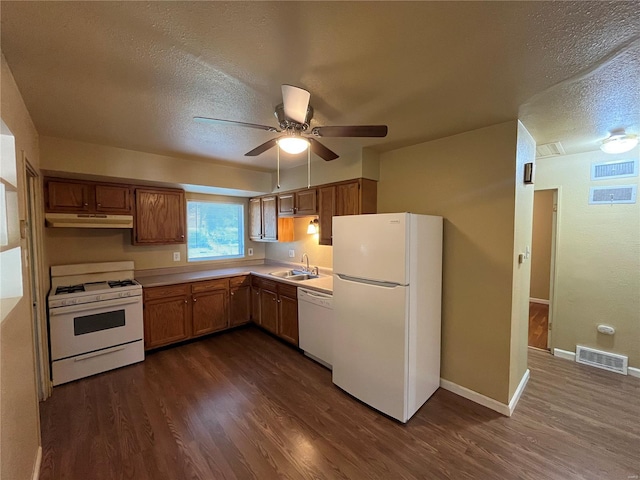 kitchen featuring a sink, white appliances, a textured ceiling, under cabinet range hood, and visible vents